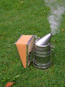 Beekeeper's Smoker Photograph of beekeeping Smoker resting on the grass with smoke exuding from it